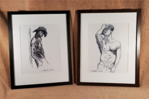 Two drawings of gay shirtless cowboys framed in black.